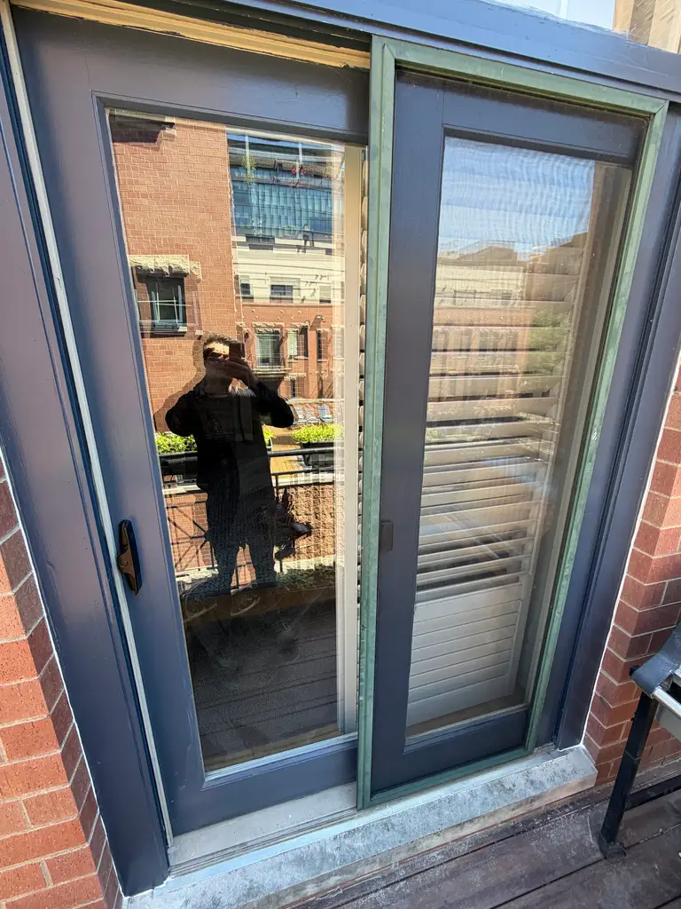 Dark sliding glass door and screen on a brick balcony