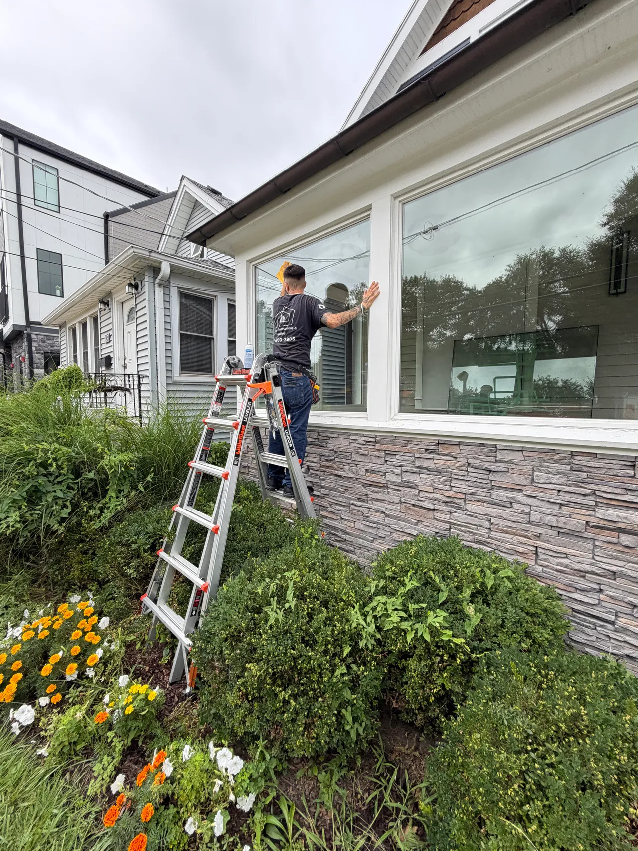 Technician on a ladder setting glass in a bay window
