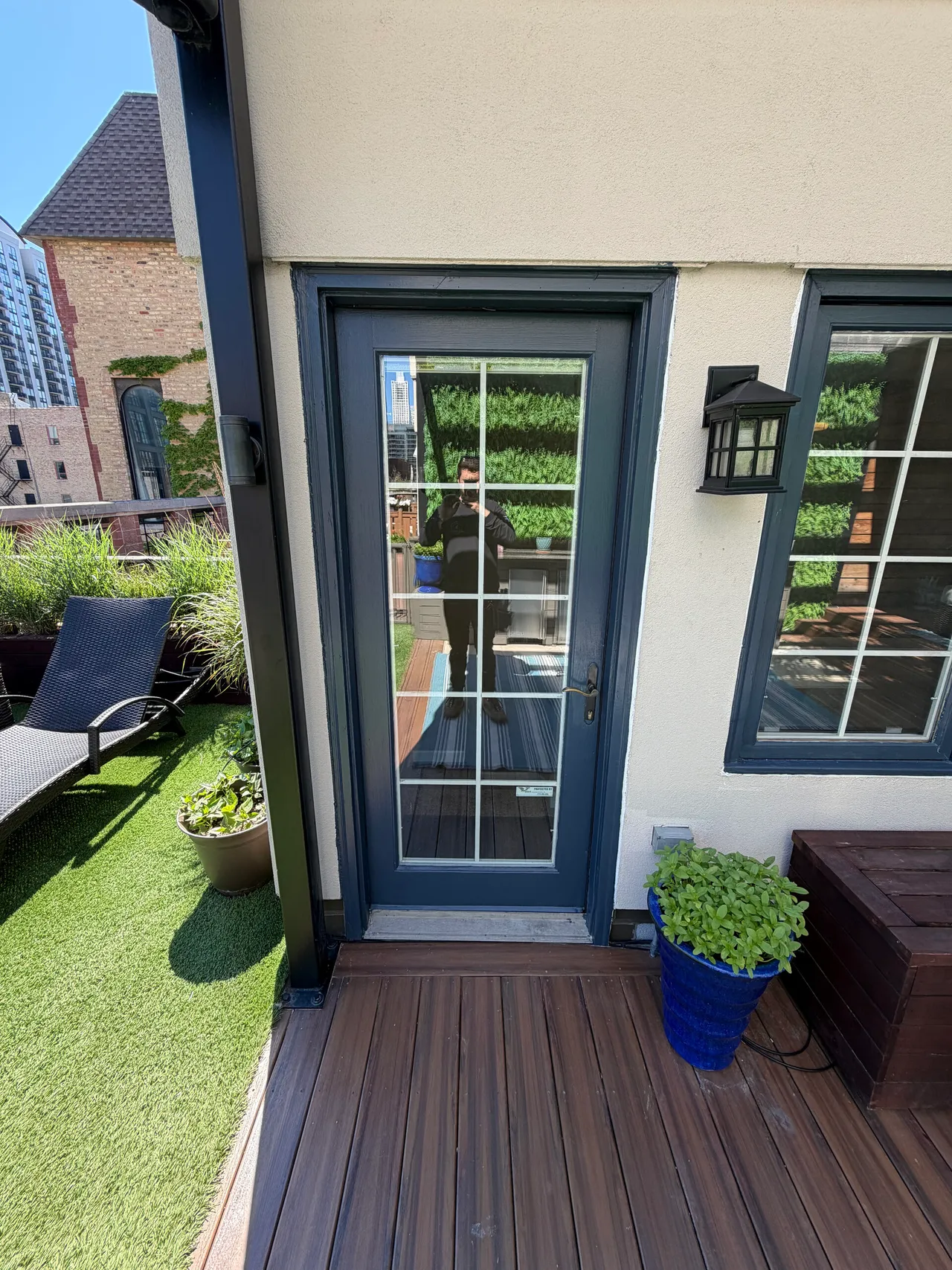 Dark French door with divided lights beside a window on a wood deck