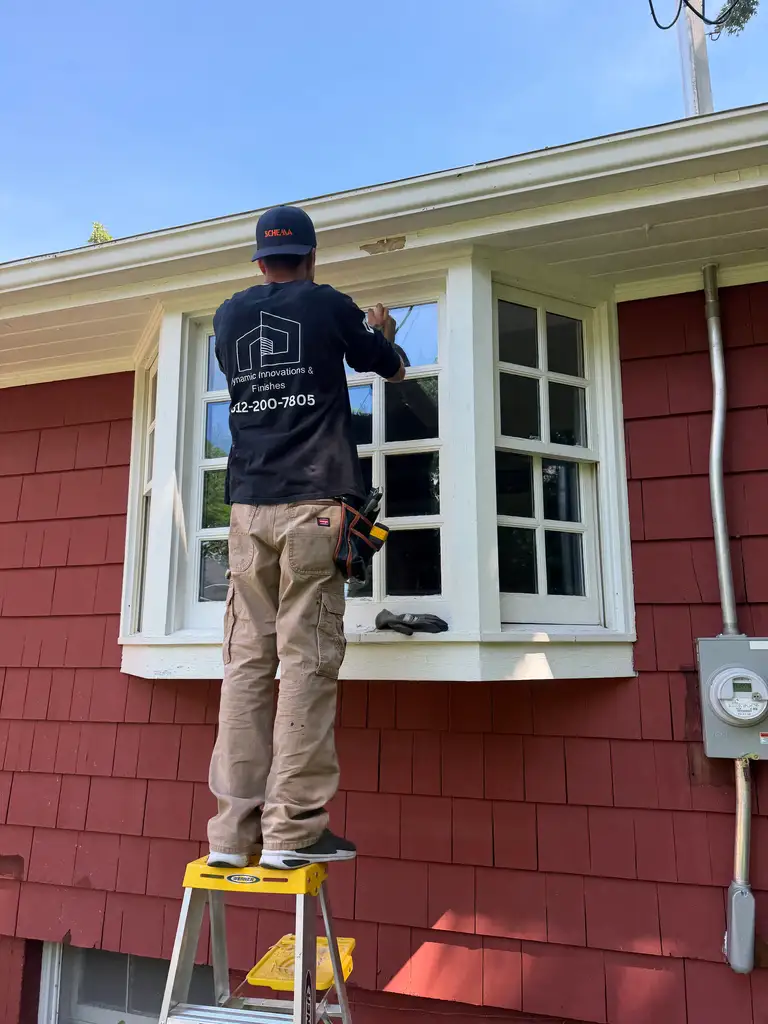 Technician on a ladder repairing a double-hung window