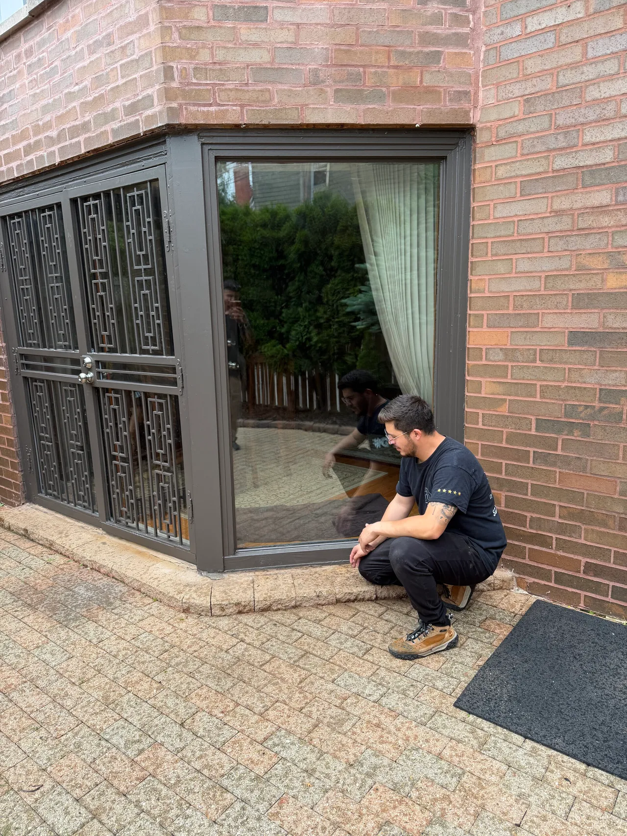 Technician crouched beside a corner window on a Kenwood brick house